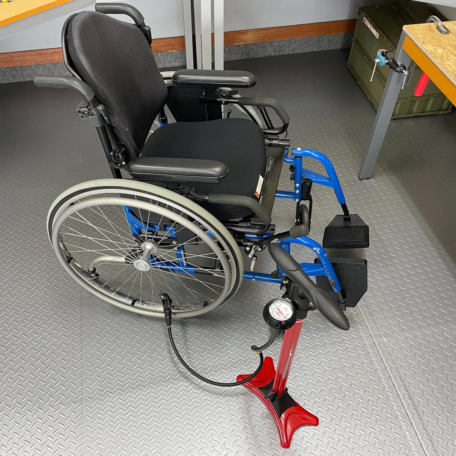 車いすのタイヤを空気圧計付きポンプで点検する様子